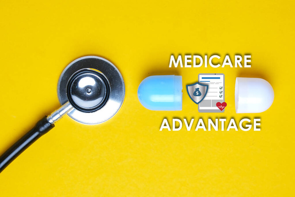 Een beeld van stethoscoop met nep capsule, medicare voordeel woord, tablet, geld schild en hart. - Foto, afbeelding