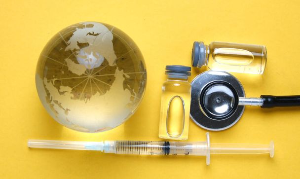 Een foto van vaccin en stethoscoop met glazen wereldbol inzicht. Zorg goed voor jezelf tijdens deze pandemie. - Foto, afbeelding