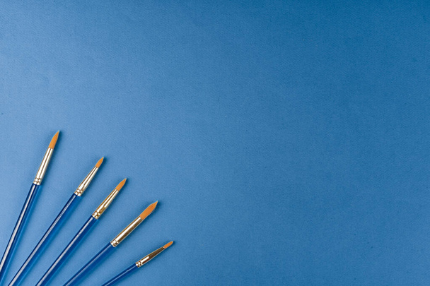 Blue paint brushes on classic blue background, view from above - Φωτογραφία, εικόνα