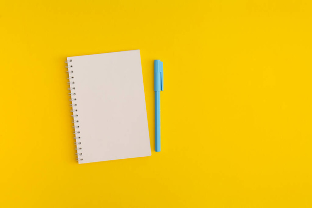 Notebook and pen on yellow background. Top view. Flat lay. Back to school concept. - Foto, imagen