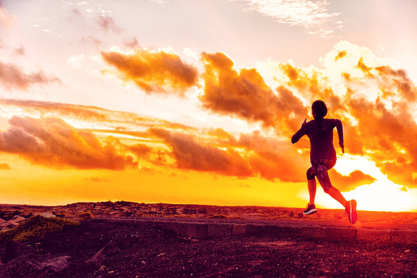 Fitness training sports athlete running in sunset - Silhouette of girl jogging on trail road with orange sky background. Fit woman exercise lifestyle. Active people. - Φωτογραφία, εικόνα