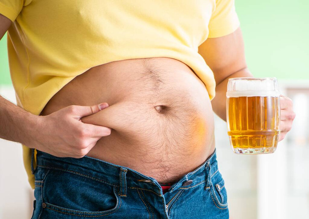 Жирний чоловік тримає пиво в концепції дієти
 - Фото, зображення