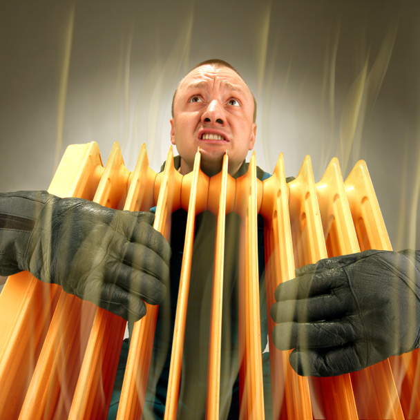 Замораживающий человек держит горячий масляный радиатор
 - Фото, изображение