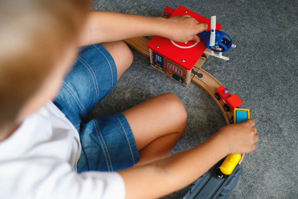 A fiú a játékfa úton játszik. Első látásra. Gyerek fiú játszik a szobájában egy játék vonat. - Fotó, kép