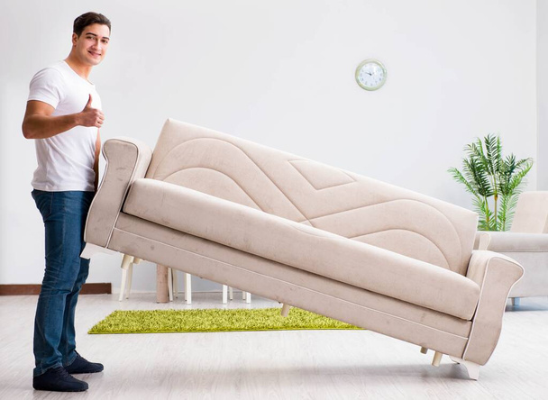 Junger Mann bewegt Möbel zu Hause - Foto, Bild