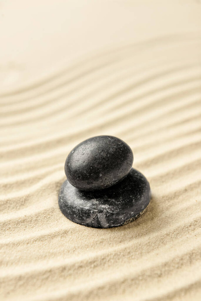 Piedras de spa negras sobre arena clara - Foto, imagen