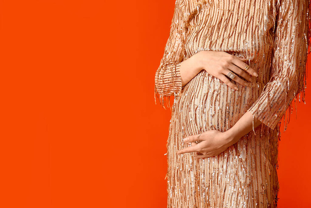 Stylish young pregnant woman on red background - Foto, imagen