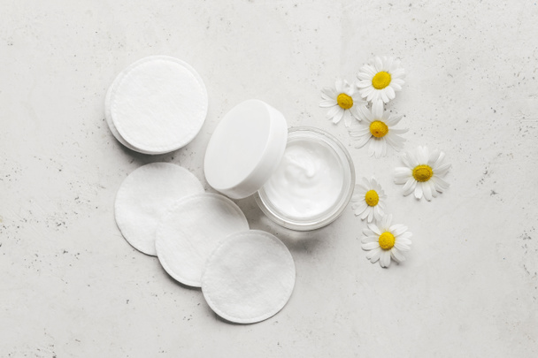 Clean cotton pads, face cream and Chamomile flowers on light background - Photo, Image