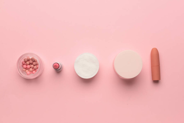 Blushes, lápices labiales, crema facial y almohadillas de algodón sobre fondo rosa - Foto, imagen