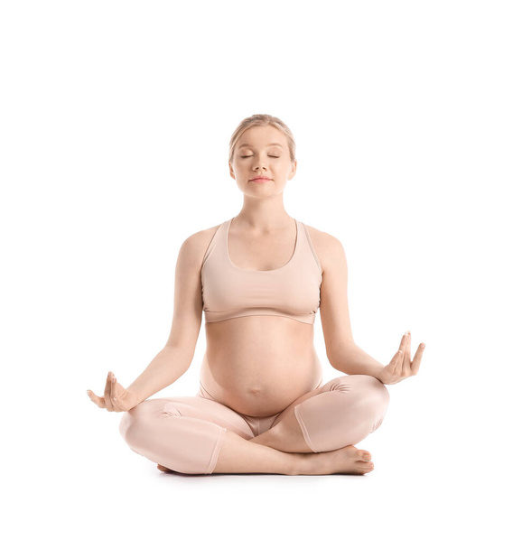 jonge zwangere vrouw mediteren op witte achtergrond - Foto, afbeelding