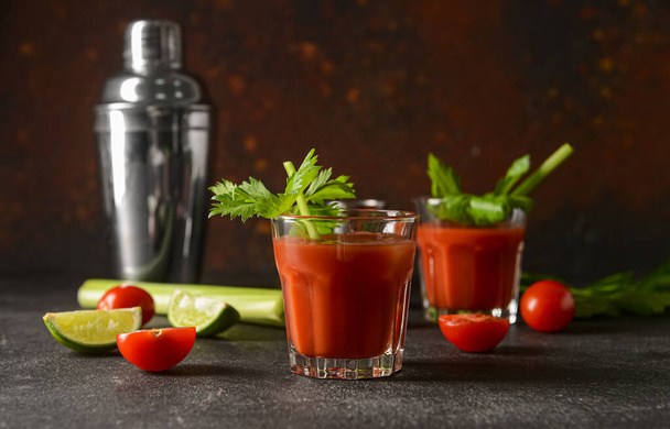 Glass of bloody mary with celery, lime and tomatoes on table - Photo, Image