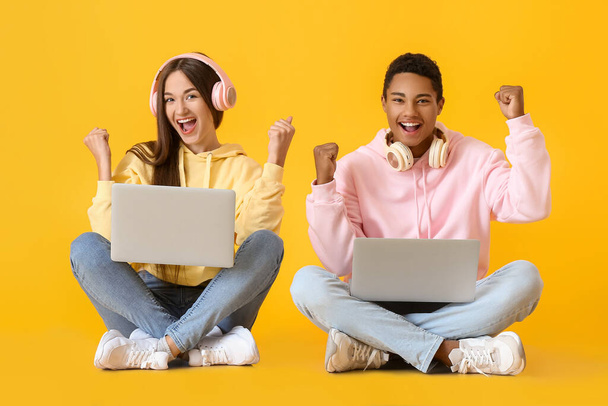 Stylowa młoda para w kapturach z laptopem na żółtym tle - Zdjęcie, obraz