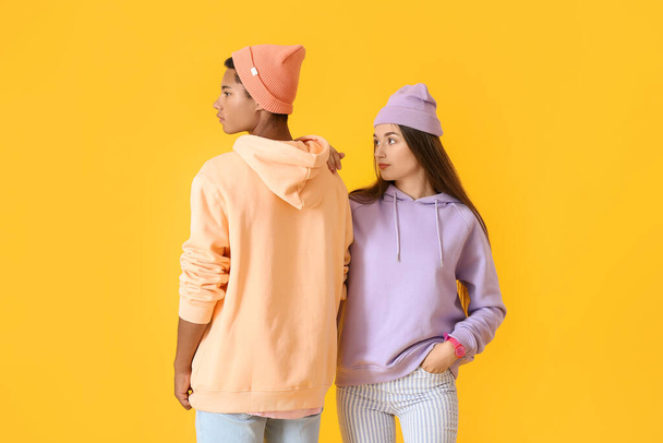 Stylish young couple in hoodies on yellow background - Photo, Image
