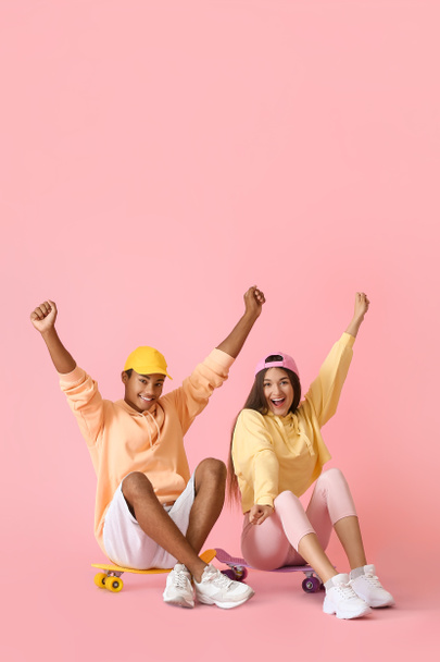 Стильная молодая пара фигуристов в толстовках на розовом фоне - Фото, изображение
