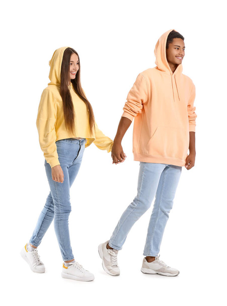 Stylish young couple in hoodies holding hands on white background - Foto, Imagem