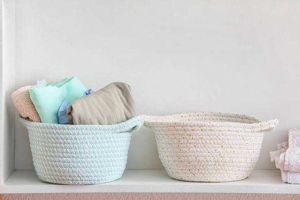 Baskets with clean clothes on shelf, closeup - Foto, afbeelding