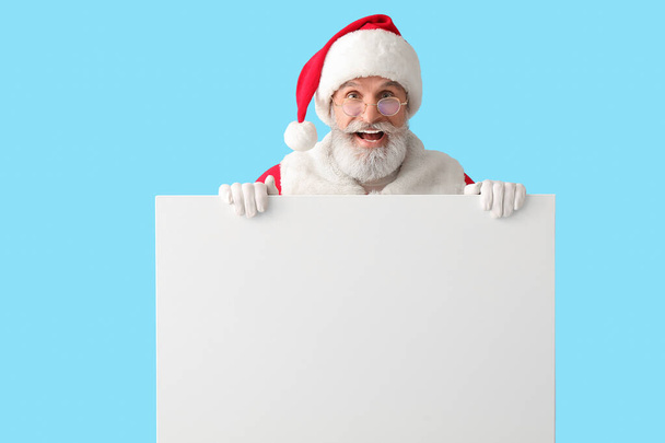 Santa Claus with blank poster on color background - Foto, imagen