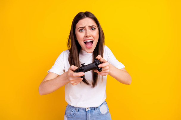 Photo of young girl unhappy play video game joystick angry lose competition isolated over yellow color background - Foto, Bild