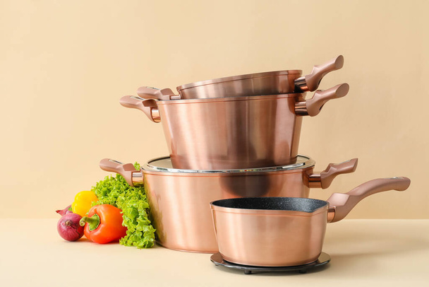 Set of different cooking pots with vegetables on color background - Photo, Image