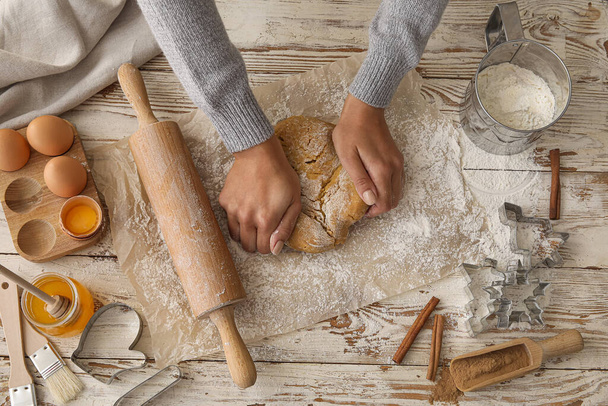 Woman kneading gingerbread dough on table - Foto, afbeelding