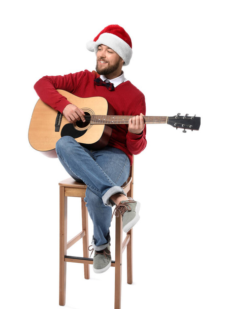 Young man in Santa hat playing guitar on white background - Photo, Image