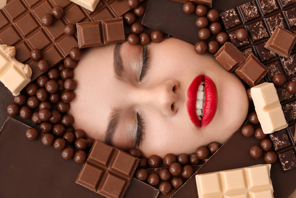 Volto di bella giovane donna circondata da diversi dolci al cioccolato - Foto, immagini