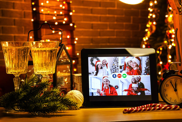 Tablet υπολογιστή στο τραπέζι στο σκοτεινό δωμάτιο. Γιορτάζοντας τα Χριστούγεννα σε απευθείας σύνδεση λόγω της επιδημίας coronavirus - Φωτογραφία, εικόνα