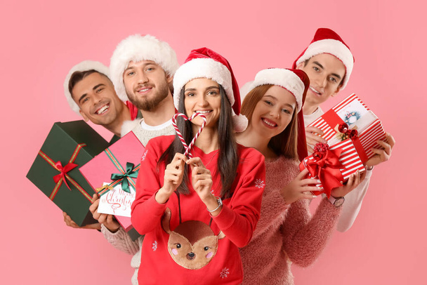 色の背景にクリスマスプレゼントやキャンディーの缶を持つ友人のグループ - 写真・画像