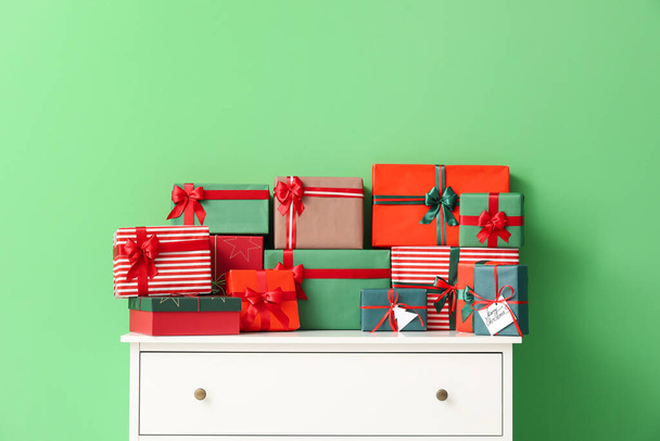 Cómoda con diferentes regalos de Navidad sobre fondo de color - Foto, imagen