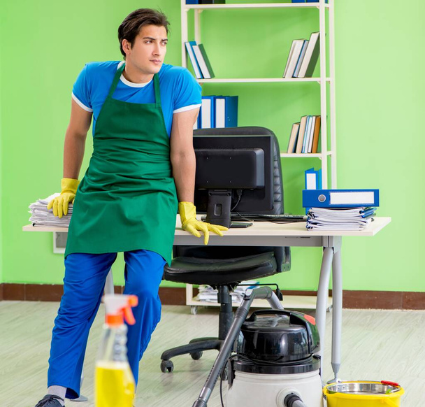 Hombre guapo limpieza oficina con aspiradora - Foto, imagen