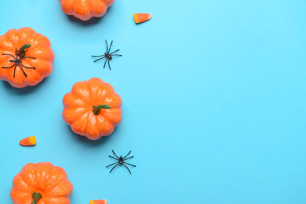 Pumpkins with spiders and candies on blue background - Photo, Image