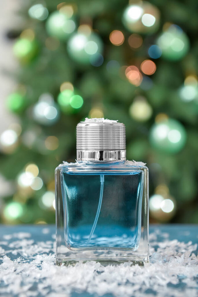 Perfume bottle and Christmas balls on table against blurred background - Foto, immagini