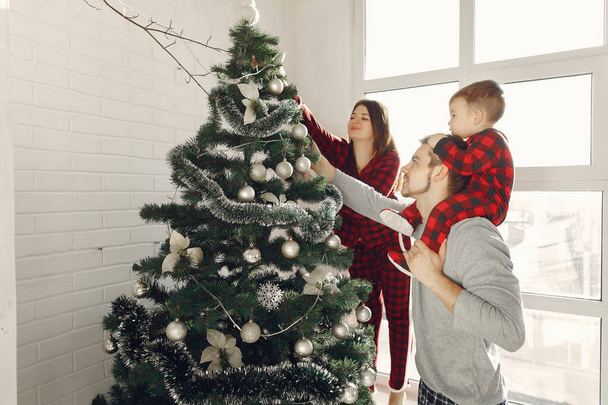 Family with little son at home near christmas tree - Foto, Imagen