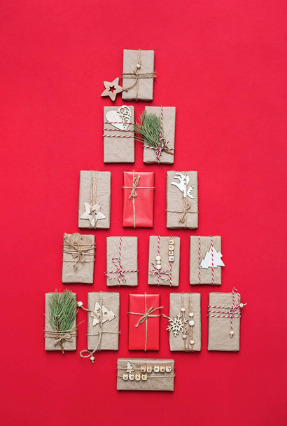 Christmas tree made from gifts. Gift boxes on red background, flat lay. Christmas holiday concept. - Photo, Image