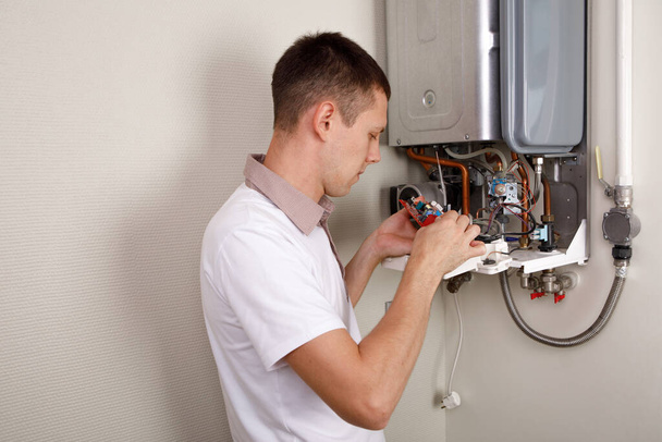 Plumber attaches Trying To Fix the Problem with the Residential Heating Equipment. Repair of a gas boiler - Foto, immagini