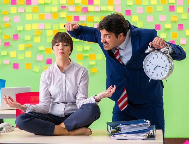 Мужчина и женщина в офисе со многими противоречивыми приоритетами в - Фото, изображение