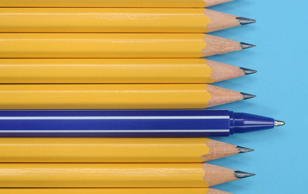 青い背景に黄色の鉛筆と青いペン。最上階だ。違いの概念. - 写真・画像