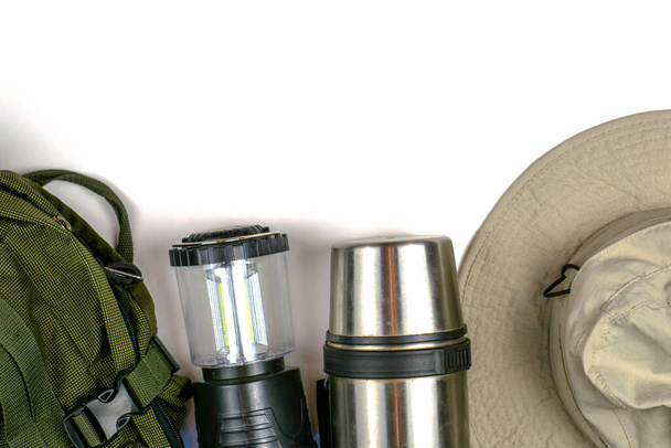 Turist sırt çantası lambası termosu ve beyaz arka planda kopyalanmış şapka - Fotoğraf, Görsel