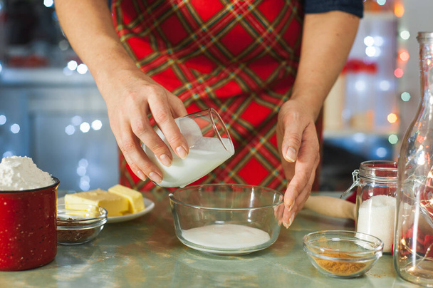 Kerst koken. Vrouwen handen bereiden deeg in glaswerk in een versierde keuken. - Foto, afbeelding