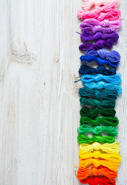 A set of multicolored threads for embroidery on wooden turquoise bacground - Фото, изображение