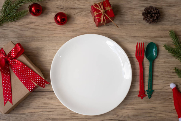 Vrolijk kerstfeest met bord, vork en lepel op houten tafelondergrond. Kerstmis, feest en gelukkig nieuwjaarsconcept - Foto, afbeelding