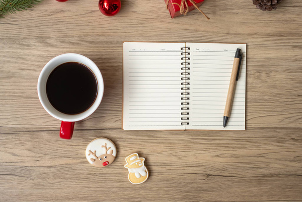 Blank notebook, black coffee cup, Christmas cookies and pen on wood table, Top view and copy space. Xmas, Happy New Year, Goals, Resolution, To do list, Strategy and Plan concept - Valokuva, kuva