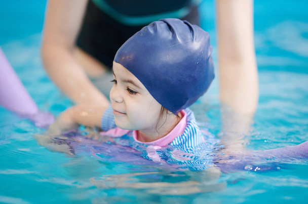 Nauczanie dzieci pływać w niebieskim basenie wody z bliska widok - Zdjęcie, obraz
