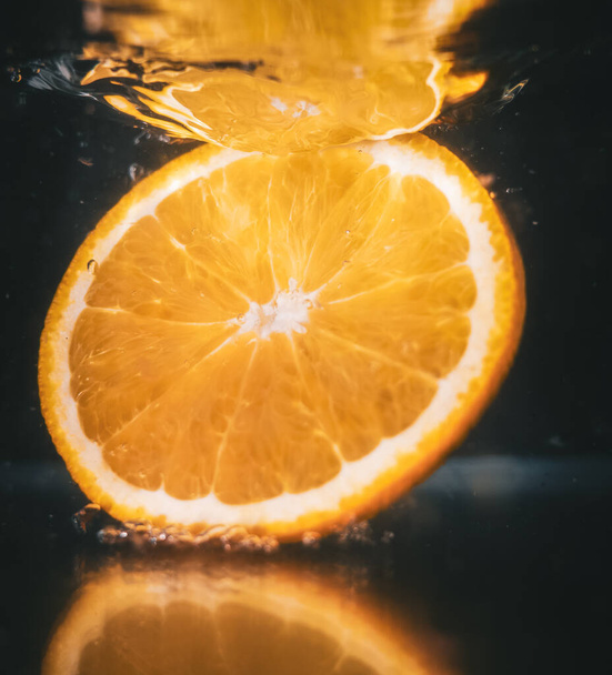 A closeup shot of an orange slice splashing in water - Foto, imagen