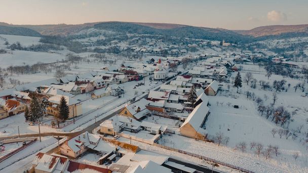 A beautiful view of the village surrounded by a snow-covered field - Fotó, kép