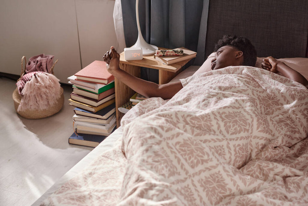 Mujer despertando con despertador en el dormitorio - Foto, Imagen