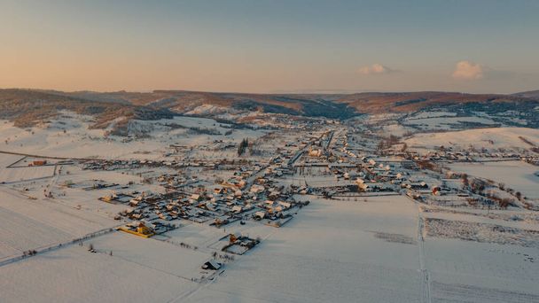 Karla kaplı bir tarla ile çevrili güzel bir köy manzarası. - Fotoğraf, Görsel