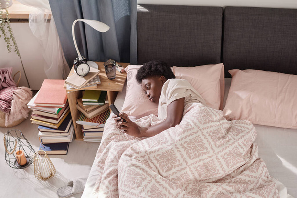 Женщина отдыхает с телефоном в спальне - Фото, изображение