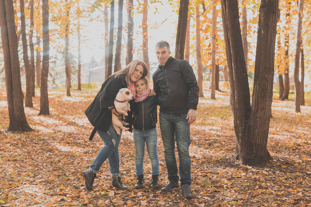 Familie brengt tijd door in het herfstpark met een hond. Vader, moeder en dochter en Jack Russell terriër hond hebben plezier in de herfst - Foto, afbeelding