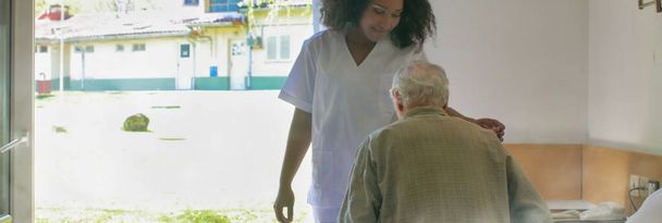 Joven doctora africana ayudando a ancianos jubilados en la cama del hospital. - Foto, Imagen